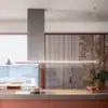 Falmec hood Lumen Island 175 Inox three-quarter view with cooktop, water view, and terracotta louvres