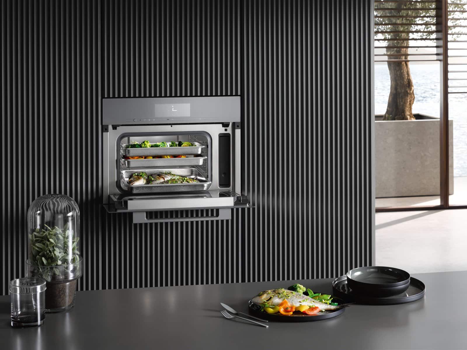 Built-in Miele compact oven with steamed dishes on its trays