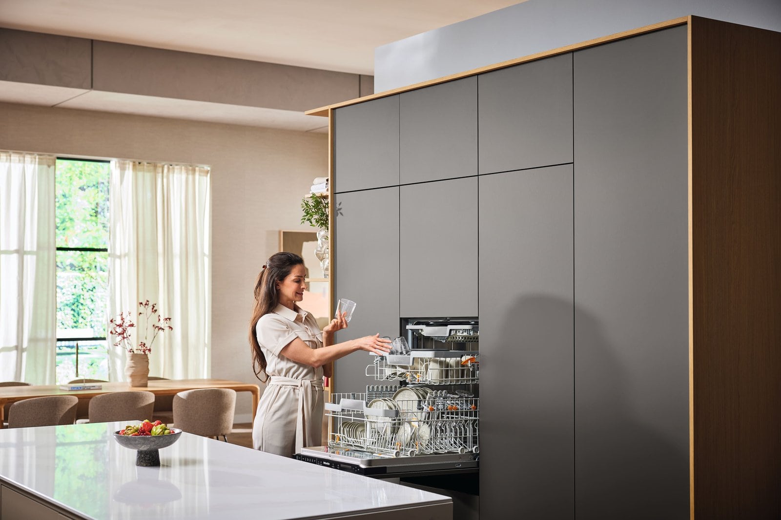 Loading glasses into a built-in Miele dishwasher in a minimalist kitchen