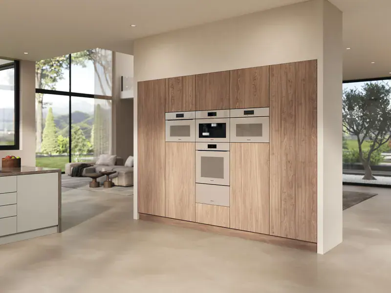 Bright kitchen with a column of Miele ovens in wood units